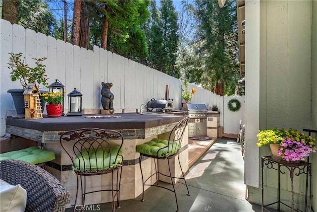 view of patio / terrace featuring area for grilling, fence, grilling area, and outdoor wet bar