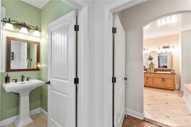 bathroom featuring baseboards, tile patterned floors, and a sink