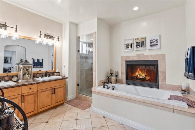 bathroom featuring a sink, a fireplace, tile patterned floors, a garden tub, and a stall shower