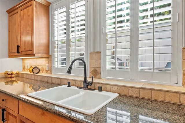 kitchen featuring backsplash, brown cabinets, a wealth of natural light, and a sink