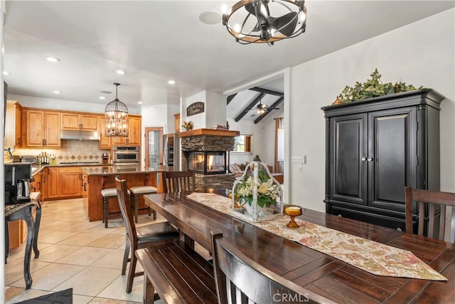 dining room featuring recessed lighting, ceiling fan with notable chandelier, light tile patterned floors, and a stone fireplace