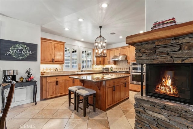 kitchen with under cabinet range hood, stainless steel appliances, a sink, and tasteful backsplash