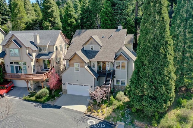 view of front of home with stone siding, a garage, stairway, a chimney, and concrete driveway