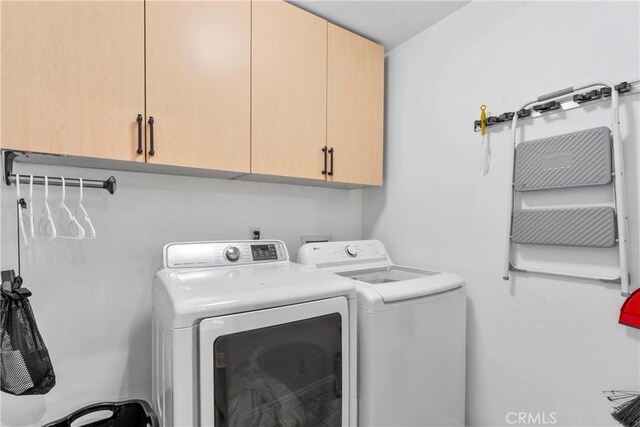 clothes washing area featuring cabinet space and washer and dryer