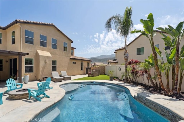 view of pool featuring an outdoor fire pit, a fenced backyard, a mountain view, and a patio