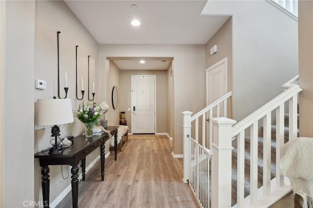 hall featuring light wood finished floors, recessed lighting, baseboards, and stairway