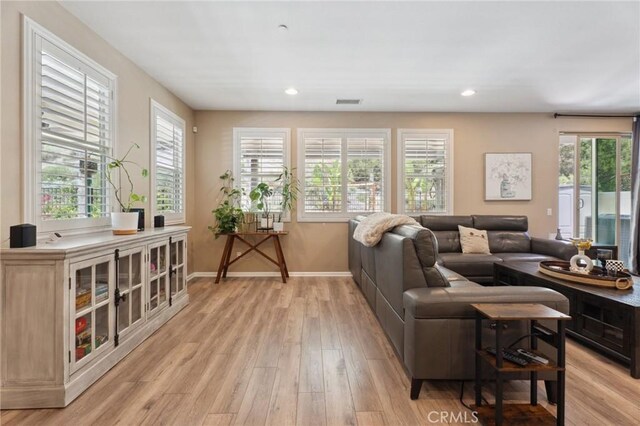 living room with baseboards, light wood-type flooring, and recessed lighting