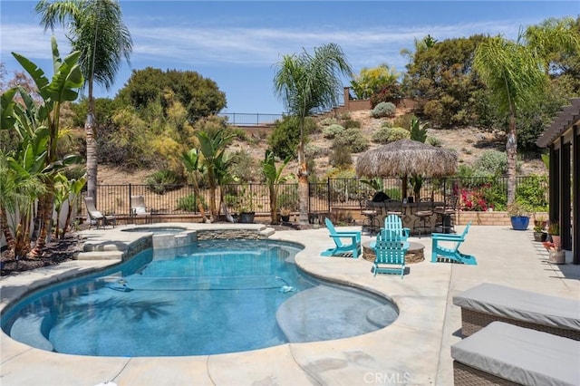 view of swimming pool with a patio area, fence, and a pool with connected hot tub