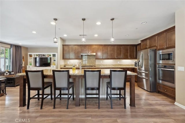 11266 Hutton Rd, Corona, CA 92883 - kitchen featuring appliances with stainless steel finishes, light stone counters, decorative light fixtures, light wood-style flooring, and under cabinet range hood
