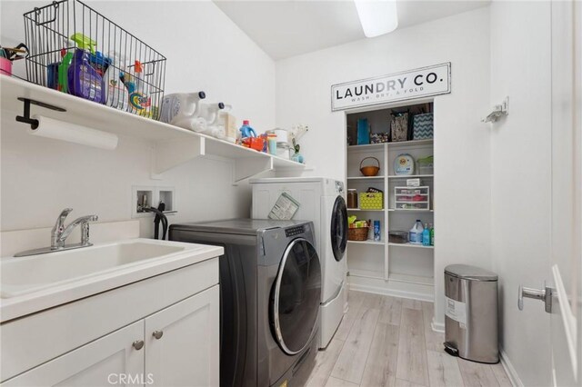 laundry room with washer and clothes dryer, light wood-style flooring, cabinet space, and baseboards
