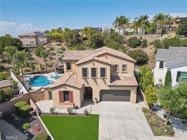 mediterranean / spanish home with a tile roof, an attached garage, stucco siding, concrete driveway, and fence