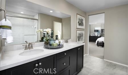 ensuite bathroom featuring double vanity, a sink, baseboards, and ensuite bathroom