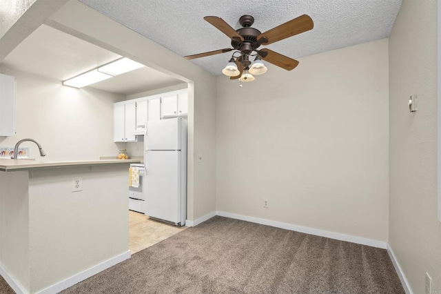 kitchen featuring a peninsula, ceiling fan, light carpet, and white appliances