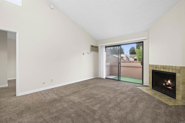 unfurnished living room with a tiled fireplace, a wall mounted air conditioner, baseboards, high vaulted ceiling, and carpet flooring