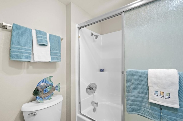 bathroom featuring combined bath / shower with glass door and toilet