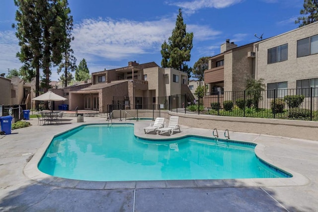 pool featuring a patio, fence, and a residential view