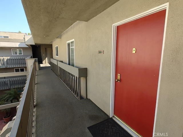 view of exterior entry featuring a balcony and stucco siding