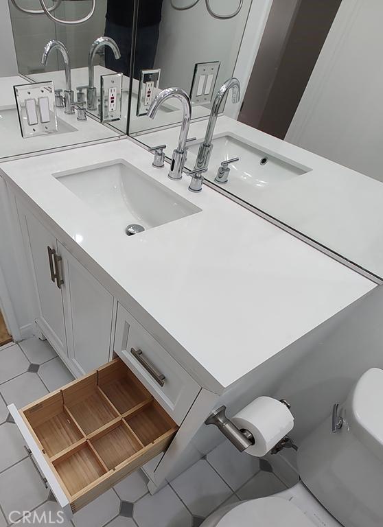 bathroom featuring double vanity, a sink, and toilet
