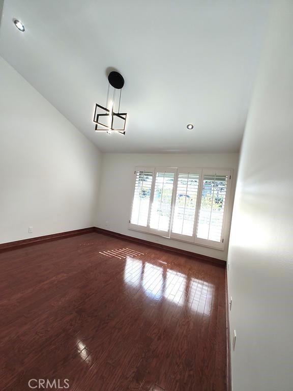 unfurnished room featuring recessed lighting, baseboards, an inviting chandelier, and wood finished floors