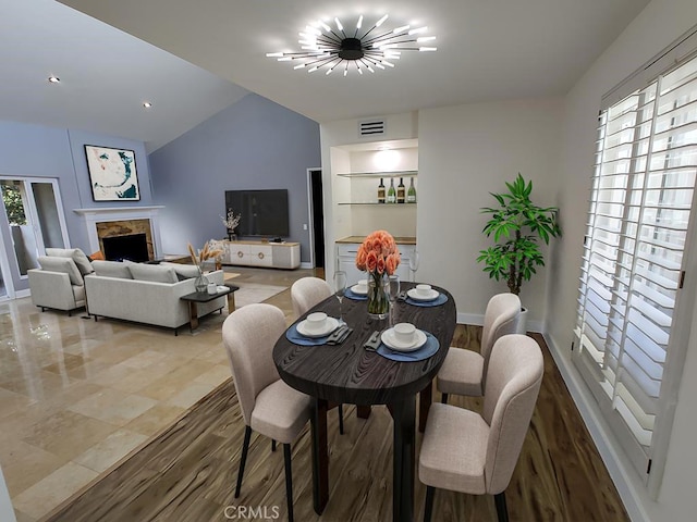 dining area featuring visible vents, baseboards, light wood-style floors, a chandelier, and vaulted ceiling