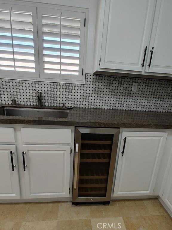 interior space with backsplash, beverage cooler, and a sink