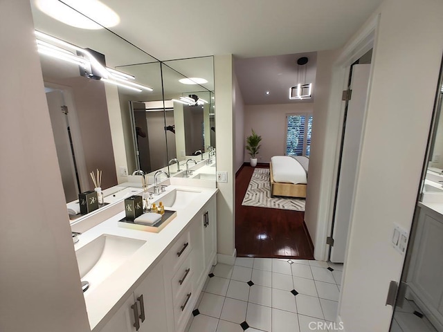 ensuite bathroom with a sink, tile patterned floors, double vanity, and connected bathroom