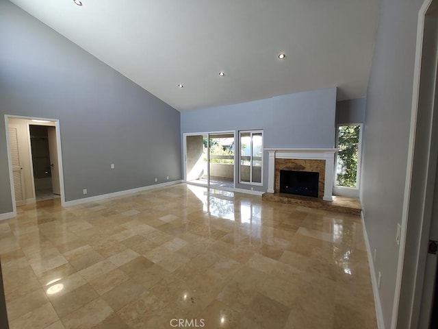 unfurnished living room featuring baseboards, a fireplace with raised hearth, recessed lighting, and high vaulted ceiling