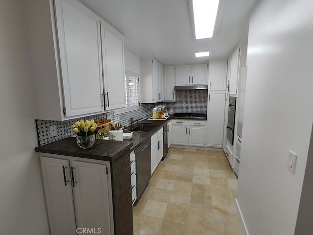 kitchen featuring white cabinets, dark countertops, a sink, dishwasher, and tasteful backsplash