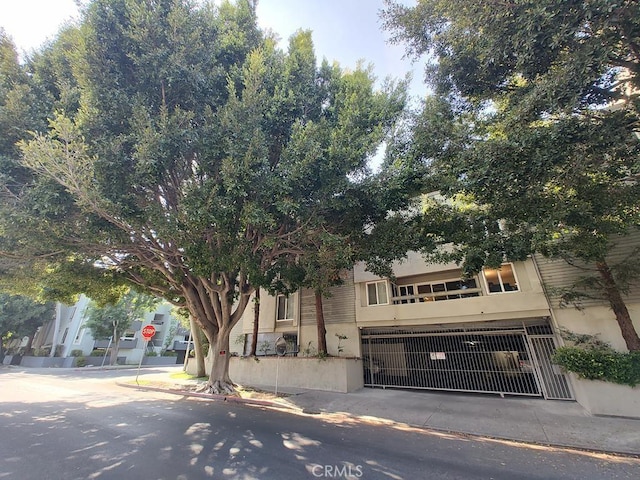 view of property hidden behind natural elements with a gate and stucco siding