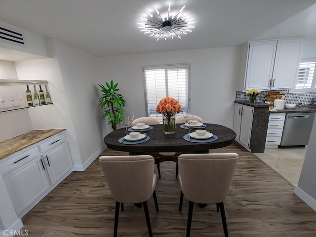 dining space featuring a chandelier, baseboards, visible vents, and light wood-style flooring