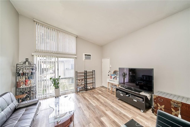 living area with light wood-style flooring, high vaulted ceiling, and an AC wall unit
