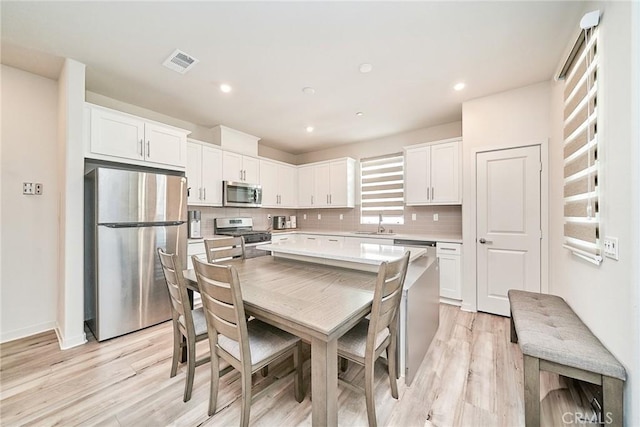 163 Dove Lndg, Covina, CA 91722 - kitchen featuring stainless steel appliances, white cabinets, light wood-style flooring, light countertops, and backsplash