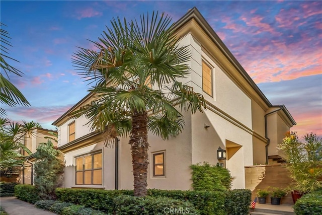 property exterior at dusk featuring stucco siding