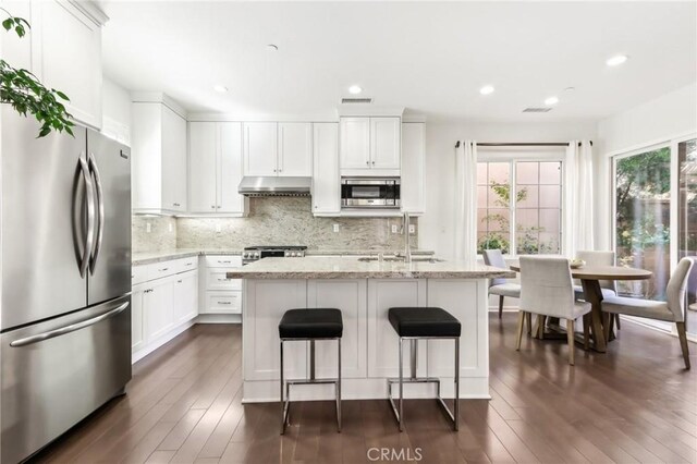 kitchen with stainless steel appliances, under cabinet range hood, healthy amount of natural light, backsplash, and recessed lighting