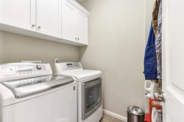 laundry room featuring washing machine and clothes dryer, cabinet space, tile patterned flooring, and baseboards