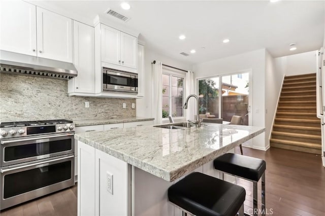 kitchen with under cabinet range hood, a sink, appliances with stainless steel finishes, dark wood-style flooring, and recessed lighting