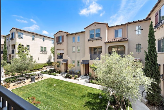 exterior space featuring stucco siding, a yard, and a tile roof