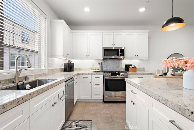 kitchen featuring a sink, appliances with stainless steel finishes, light tile patterned flooring, and white cabinets