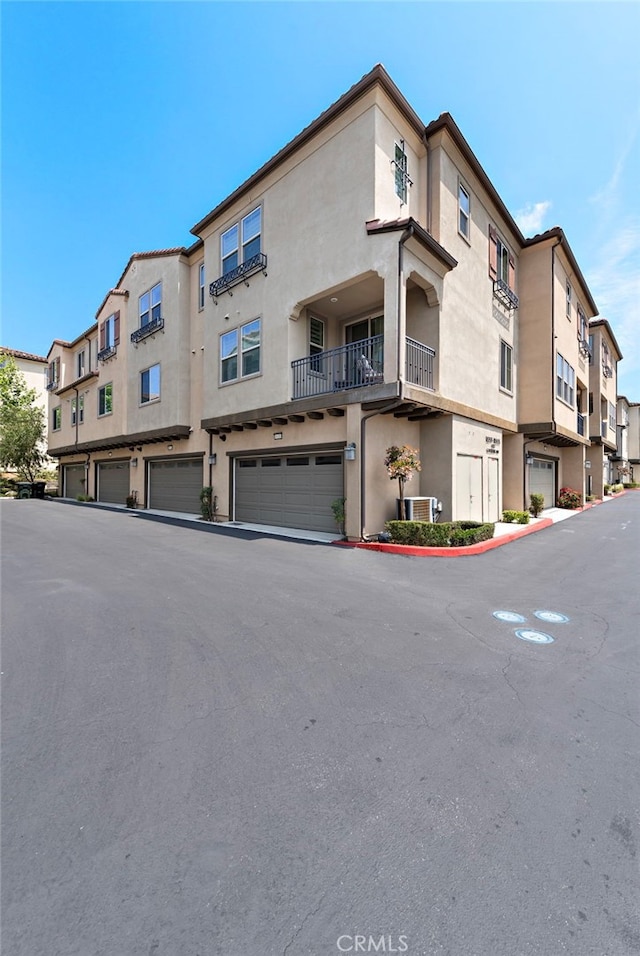 view of property featuring an attached garage, a residential view, and central AC unit