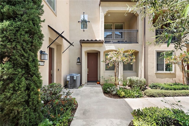 doorway to property featuring stucco siding, a balcony, and cooling unit