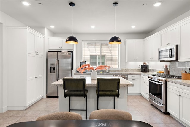 kitchen with a kitchen island, stainless steel appliances, white cabinetry, and light tile patterned flooring