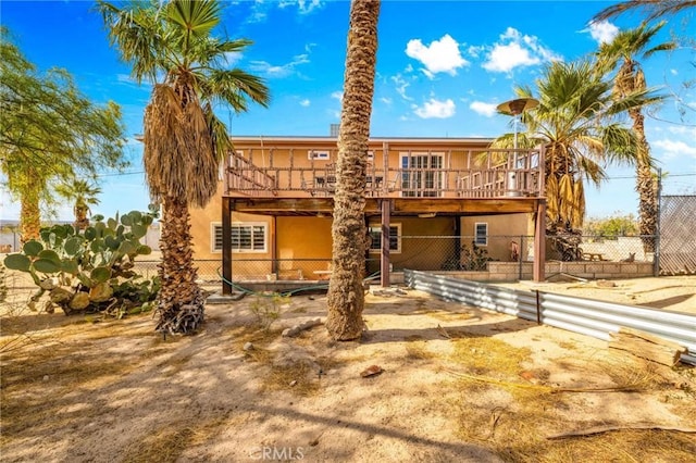 back of property featuring fence, a wooden deck, and stucco siding
