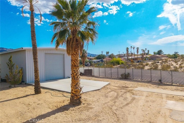 view of yard with fence, an outdoor structure, driveway, and a residential view