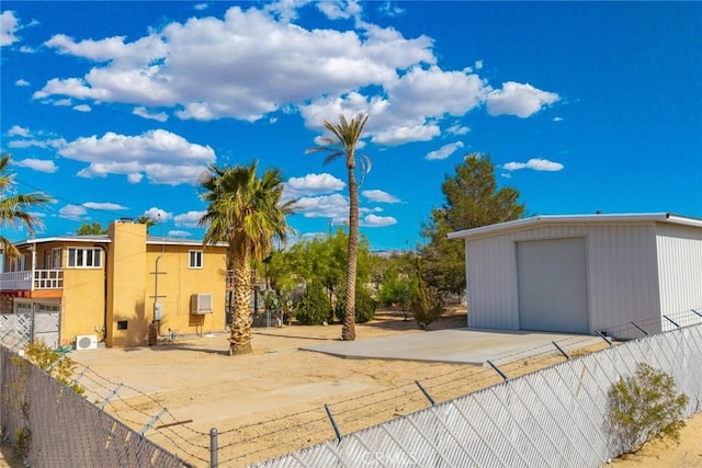 exterior space with fence, a detached garage, and an outdoor structure