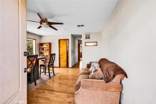 living room with a ceiling fan, visible vents, and light wood-style flooring