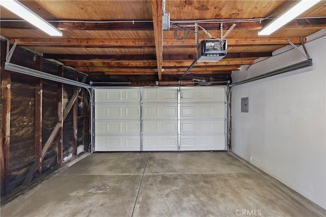 garage with baseboards, a garage door opener, and electric panel