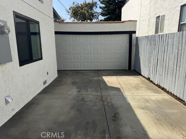 garage featuring concrete driveway and fence