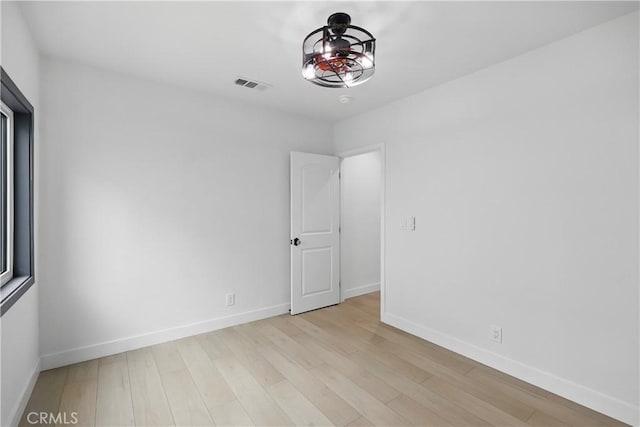 unfurnished room featuring baseboards, light wood-type flooring, and visible vents