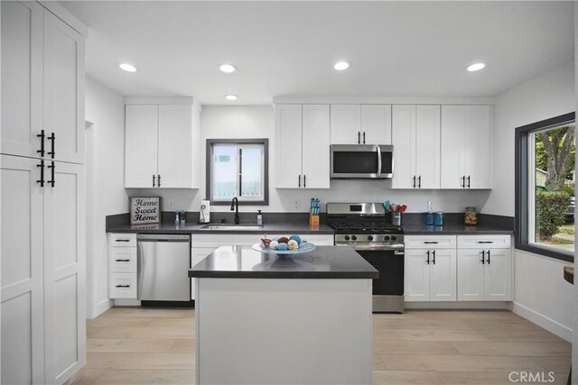 8313 Washington Ave, Whittier, CA 90602 - kitchen featuring stainless steel appliances, a sink, light wood-type flooring, white cabinetry, and dark countertops