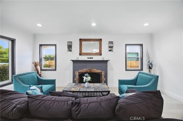 living area featuring recessed lighting, baseboards, a stone fireplace, and wood finished floors